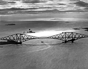 A Royal Navy battleships passes underneath the Forth bridges it prepares to dock