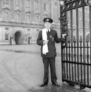 The Royal Postman stands at the gates to Buckingham Palace before collecting Queen