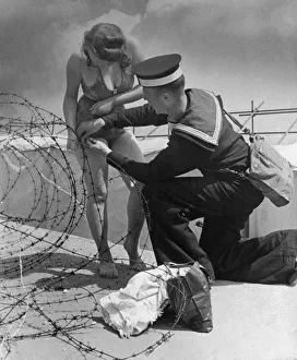 Helping Prints: A sailor lends a hand when a female holidaymaker becomes entangled in barbed wire