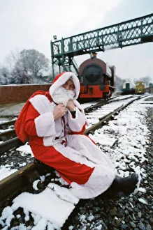 Santa stopped in his tracks. Father Christmas sitting on railway tracks