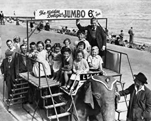 Rides Prints: Scene at the beach at Colwyn Bay in North Wales showing children sitting on a wooden