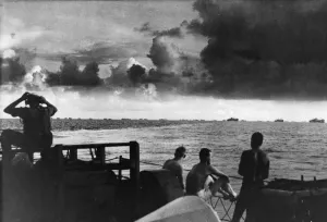 Seamen on the deck of a US Coast Guard Frigate watch a large caravan of ships