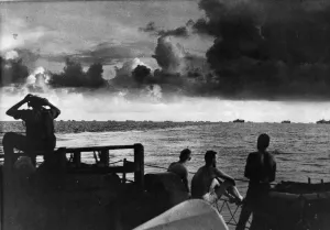 Seamen on the deck of the US Coast Guard Frigate watch a large caravan of ships