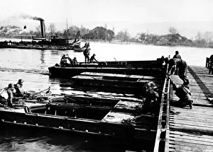 Regiment Prints: Section of army treadway bridge is pushed into place by landing craft personnel