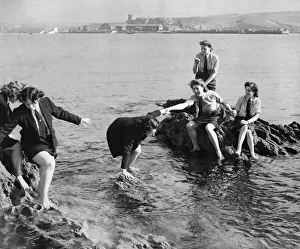 Service girls caught on the rocks in Plymouth, Devon. The US soldiers nearby
