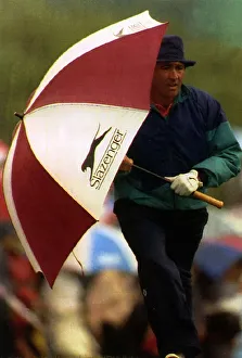 00134 Prints: Seve Ballesteros holding a golf umbrella at his side whilst walking to the next hole