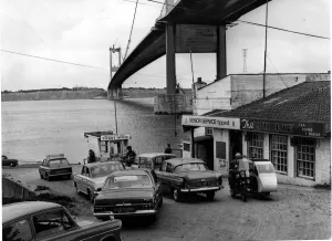 Severn Ferry - Cars queue up for the ferry with the recently completed bridge towering