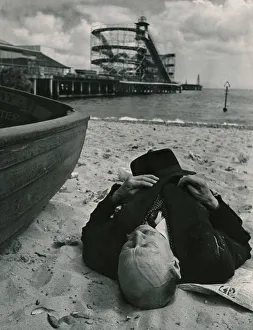 Sheltered from the squalls in the Whitsun sunshine this holiday maker sleeps on the beach