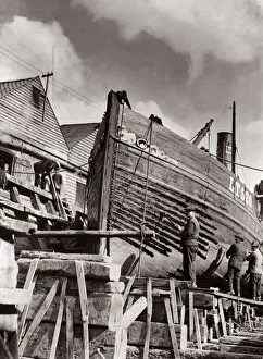 Shipyard workers re caulking a Lowestoft herring boat on stocks in dry dock Circa