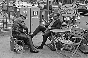 Leather Jacket Prints: A Shoe Shine goes to work on a clients shoes close to the underground station