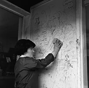 Graffiti Prints: A shop assistant removes the scribbling on the wall outside her shop in Kirkby, Liverpool
