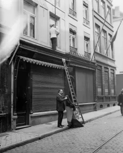 00118 Prints: Shop owners taking down the Belgium flags before Louvain is occupied by the advancing