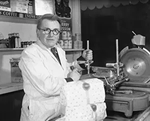 Serving Prints: Shopkeeper Kenth Shiel seen here slicing some bacon for a customer 1st January 1954