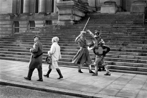 Shoppers hurry past the Town Hall steps as a couple of medieval knights are locked in