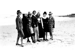 Singer Frankie Vaughan strolling along the beach with some of the models from a fashion