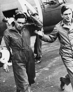 A slightly wounded and shaken waist gunner is led from his place by his flight surgeon
