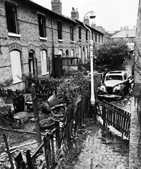 Slum housing in Birmingham. Burnt out car in the alleyway behind derelict houses