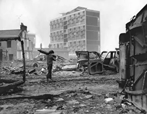 A small boy rummages among the tangled wrecks of old cars on waste ground in