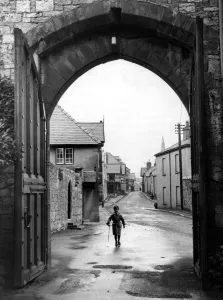 Loneliness Prints: A small boy walks through the archway at the entrance of Ruthin Castle Denbighshire