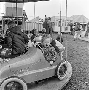 Fairs And Fairground Rides Prints: A small child enjoying the thrill of the merry-go-round at Silcocks Fair at Skelmersdale