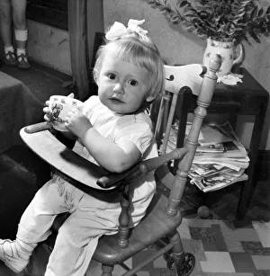 High Chair Prints: Small girl enjoying a cup of tea. August 1953 D5235-001