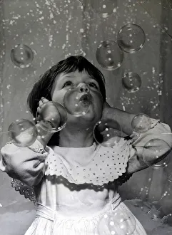 00099 Prints: Small girl fascinated by the bubble machine at the 1959 Toy Fair This is a