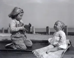 Core36 Prints: A small girl takes a picture of her little sister on Brighton beach whilst enjoying