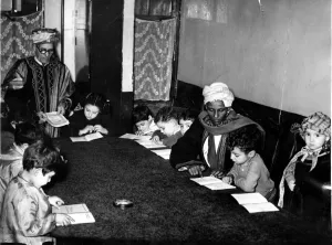 Muslim Prints: In a small room a group of children are learning the alphabet of Arabia with the Koran as