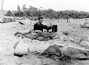 Trenches Prints: A soldier hangs a pair of socks on a washing line outside his fox hole on a French beach