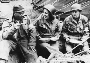 01473 Prints: US soldiers Sergeant Jim McGahan and Corporal Silvio Bescatore eat with Jean Dockholm