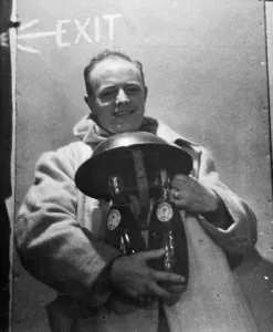 01459 Prints: A spotter in a city area finds the safe custody of his steel helmet for his two bottles