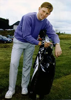 Stephen Gallacher on golf course holding golf bag containing clubs