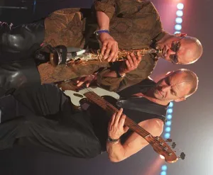 Sting rock singer performing live on stage in Aberdeen with guitar beside his saxaphone