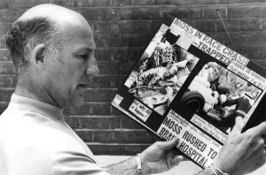 Stirling Moss reading clippings of his crash during race - August 1982