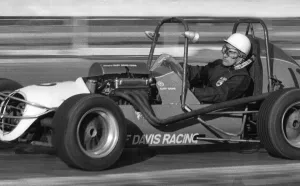 Stirling Moss rying out midget racing car at White City racing track - December 1971