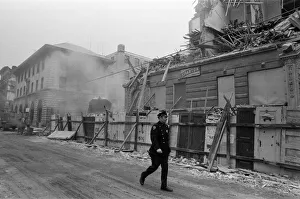 Cold Prints: Street scene in New York, a policeman walking past as a building is being demolished