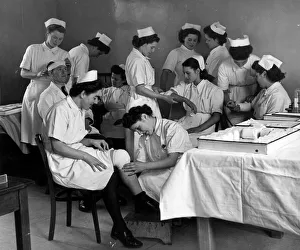 Student nurses of six nationalities learn the art of bandaging by working in pairs aand