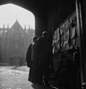 00266 Prints: Students of Oxford University check for notices on the board at the porter