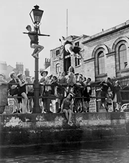 Summertime activities, children at Plymouth barbican diving if from a quayside lamp post