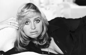 Susan George actress lying on a bed on her side holding her head up with her fingers