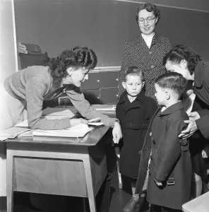 Infant School Prints: Teacher greets a new addition to her class and introduces him to one of his new class