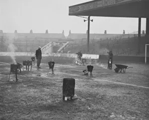 Frozen Prints: A team of four men thaw out Manchester City Football ground with braziers
