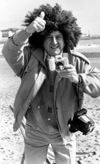 Television comedian Norman Collier wearing a funny wig on the beach April 1991