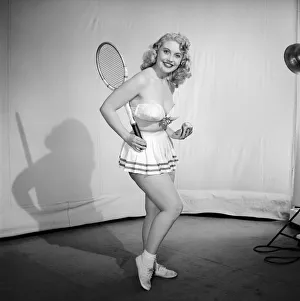 Anyone for tennis? Woman wearing bra, skirt holding tennis racket. 1959