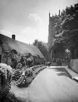 00266 Prints: Thatched roof cottages by the churching in the Cotswold village of Chipping Campden