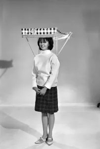 00068 Prints: Therese Howard Jones demonstrating the wear-me umbrella. Model. Circa 1959