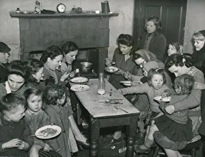 00665 Prints: Around thirty women and children enjoying their Sunday dinner in there single end at 26a