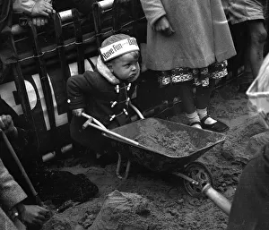 Wheelbarrow Prints: Toddler building a sandcastle at Blackpool beach August 1958