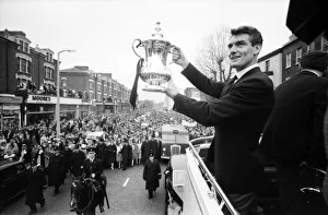 Tottenham Hotspur team hold the FA Cup trophy aloft from an open top double decker bus to