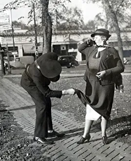 A traffic warden lifts the hem of a ladys dress to reveal her petticoats